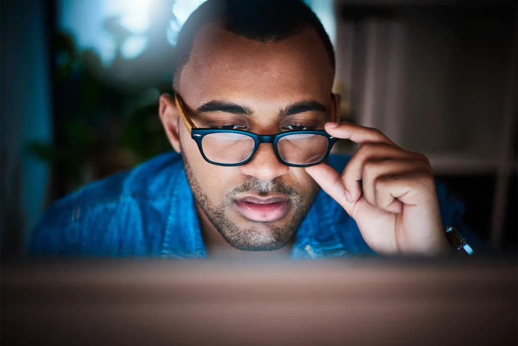 Man with glasses looking at computer at night